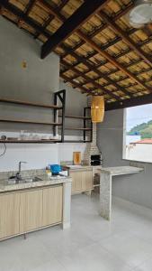 a large kitchen with counters and a large window at Casa do Sérgio, Lindo loft-02 moderno e confortável. in Paraty