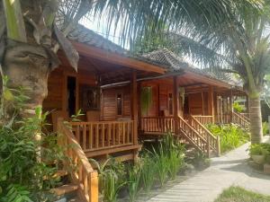 a wooden house with a porch and a palm tree at Pondok Elen Mandalika in Praya