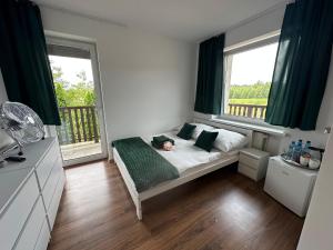 a small bedroom with a bed and two windows at Zielony Zakątek in Kobyla Góra