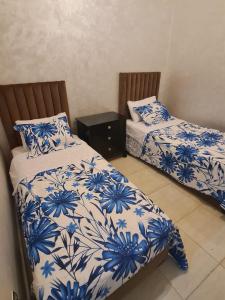 two beds in a room with blue and white sheets at Charmant appartement pour votre séjour a Bouskoura a Casablanca in Bouskoura