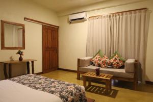 a hotel room with a bed and a couch at The Coconut Experience Eco Lodge Wilpattu in Nagamadu