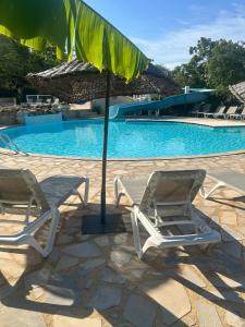 deux chaises et un parasol à côté d'une piscine dans l'établissement Europe tents Camping Le Clou, à Meynard