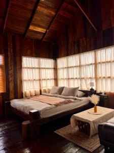 a large bed in a room with wooden walls and windows at Phu Phop Kham in Ban Huai Khai