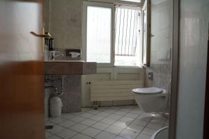 a bathroom with a toilet and a sink and a window at Hotel Porta Nigra VICTUS in Trier +17 photos