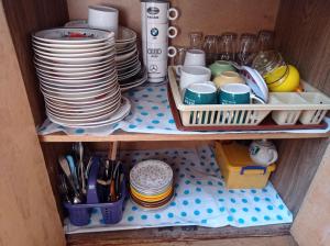 a shelf with plates and cups and utensils at House in forest in Gomi