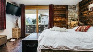 a bedroom with a large bed and a television at CHALET MOUTON a 4-Bedroom Alpine Chic Escape in Saas-Fee in Saas-Fee