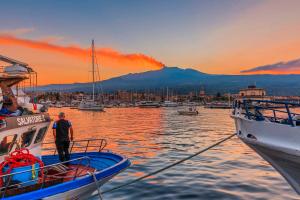 a man is standing on a boat in the water at The Cordari House in Siracusa