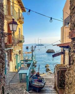 Una vista del océano desde una calle con un barco. en Villino TerrAmare, en Reggio Calabria