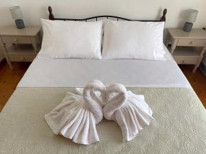 two towel swans sitting on top of a bed at Philoxenia Apartments in Samos