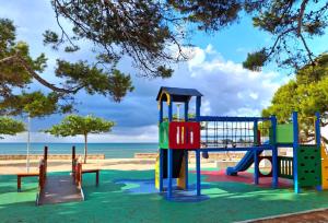 un parque infantil en la playa con el océano en el fondo en Apartamento Calablanca con amplia terraza y vistas al mar y a la montaña, en Alcossebre