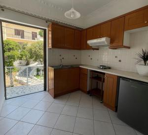 a kitchen with wooden cabinets and a large window at Philoxenia Apartments in Samos