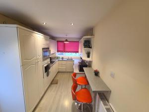 a kitchen with orange chairs and a counter and pink window at Starlet Single Room in Manchester