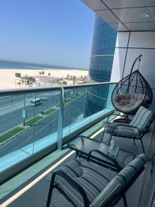 deux chaises sur un balcon avec vue sur la plage dans l'établissement Beachfront Paradise - Ajman Corniche Residence, à Ajman