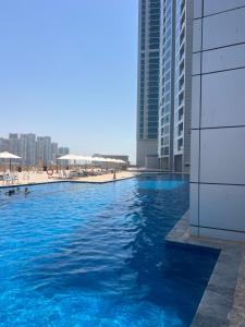 - une piscine d'eau bleue en face des bâtiments dans l'établissement Beachfront Paradise - Ajman Corniche Residence, à Ajman