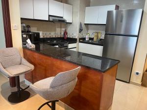 a kitchen with a counter with a refrigerator and a chair at Beachfront Paradise - Ajman Corniche Residence in Ajman 