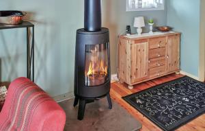 Pet Friendly Home In Snefjord With Sauna في Snøfjord: موقد في غرفة المعيشة مع أريكة حمراء