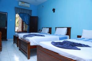two beds in a room with blue walls at Juliyanvilla in Kandy