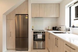 a kitchen with a stainless steel refrigerator and wooden cabinets at Luxury Apartment Christchurch Central in Christchurch