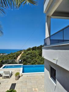 a view of a house with a swimming pool and the ocean at Apartments Merin in Utjeha