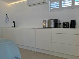 eine weiße Küche mit einer Arbeitsplatte und einer Mikrowelle in der Unterkunft 'Kaya Moya' - Luxury Suite for 2 with Ocean Views in Gordonʼs Bay + 17 Fotos