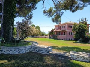 eine Steinbank vor einem rosa Haus in der Unterkunft Villa Lechonia in Káto Lekhónia