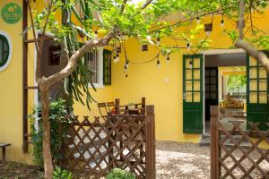 une maison jaune avec des portes vertes et une clôture dans l'établissement An Thư Home Garden, à Hue