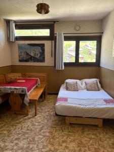 a bedroom with two beds and a table and two windows at Studio Centre Vars Le Seignon in Vars