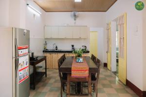 une cuisine avec une table, des chaises et un réfrigérateur dans l'établissement An Thư Home Garden, à Hue