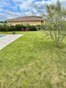 a grassy yard with two benches in front of a house at Chambre agréable, SDB privée, Clim, Vue Piscine, in Muret