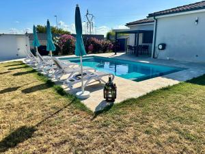 a swimming pool with chairs and umbrellas in a yard at Chambre agréable, SDB privée, Clim, Vue Piscine, in Muret