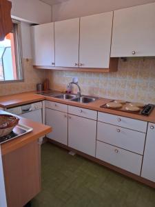 a kitchen with white cabinets and a sink at Appartement exposé plein sud in Menton