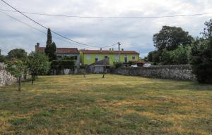 Un gran patio con una casa amarilla detrás de un muro de piedra. en apartman kostrena, en Kostrena