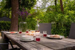 a picnic table with food and a bottle of wine at Tiny cabin in bosrijke omgeving de Veluwe - met terras, tuin en fietsschuurtje in Nunspeet +36 photos