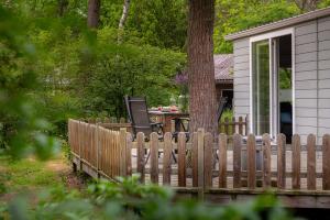 宁斯佩特Forrest Lodge in bosrijke omgeving de Veluwe - met terras, tuin en fietsschuurtje的房屋前的木栅栏