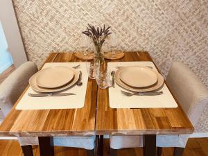 einem Holztisch mit Tellern und Besteck in der Unterkunft L'écorce marine in Sangatte