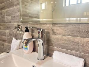 a bathroom sink with a bottle of soap and a mirror at Urban One Luxury Apartments, Kumasi - Gye Nyame in Kumasi +127 photos