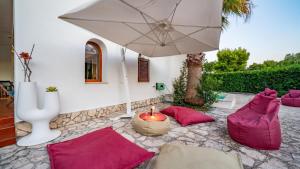 a patio with pink pillows and a candle and an umbrella at Villa Giglio with Garden and Mini Pool by Rentbeat in Rosa Marina
