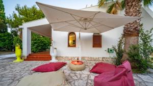 a patio with pillows and an umbrella in front of a house at Villa Giglio with Garden and Mini Pool by Rentbeat in Rosa Marina +57 photos