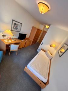 a room with a bed and a desk with a computer at Pension & Metzgerei Friedrich in Trebgast