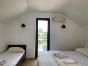 two beds in a white room with a window at Vikendica Dunja in Loznica
