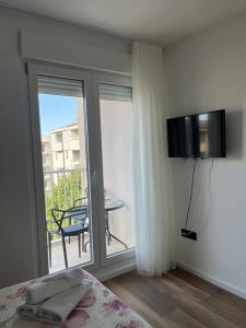 a bedroom with a bed and a balcony with a table at Apartman D11 in Ljubuški