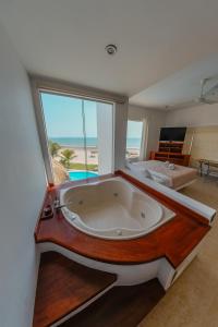 a bath tub in a room with a large window at Hotel Beso de Sal Resort in Colán