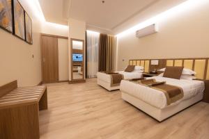 a hotel room with two beds and a couch at Sakura City Hotel in Al Baha