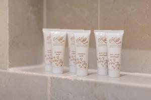 a group of four white tubes of toothbrushes on a shelf at Sakura City Hotel in Al Baha