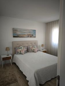 a bedroom with a large white bed with two tables at Gina House in Nazaré