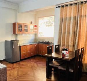 a kitchen with a table and a refrigerator at Verma paradise in Solan