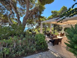 a patio with tables and chairs under a white umbrella at Hotel La Vela in Isole Tremiti