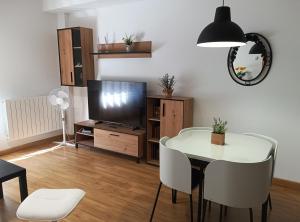 a living room with a white table and a tv at Monte Dobra in Los Corrales de Buelna