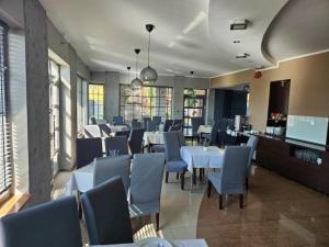 a restaurant with white tables and blue chairs at Eurybia in Łeba
