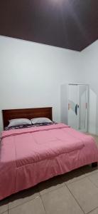 a bed with a pink comforter in a bedroom at White Guest House in Sekongkang